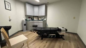 Paciente latino recibiendo atención en una clínica quiropráctica en español, con un doctor explicándole el tratamiento en su idioma.