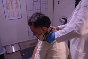 Doctor quiropráctico realizando un ajuste de columna a un paciente para corregir la causa del dolor de manera natural y sin medicamentos.