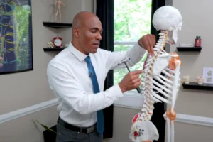 Quiropráctico explicando qué es una subluxación vertebral con modelo de columna, mostrando cómo afecta la alineación y los nervios.