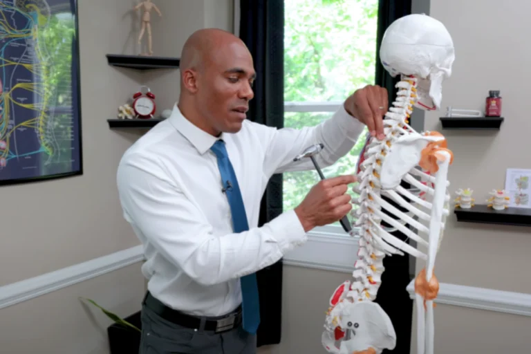 Quiropráctico explicando qué es una subluxación vertebral con modelo de columna, mostrando cómo afecta la alineación y los nervios.