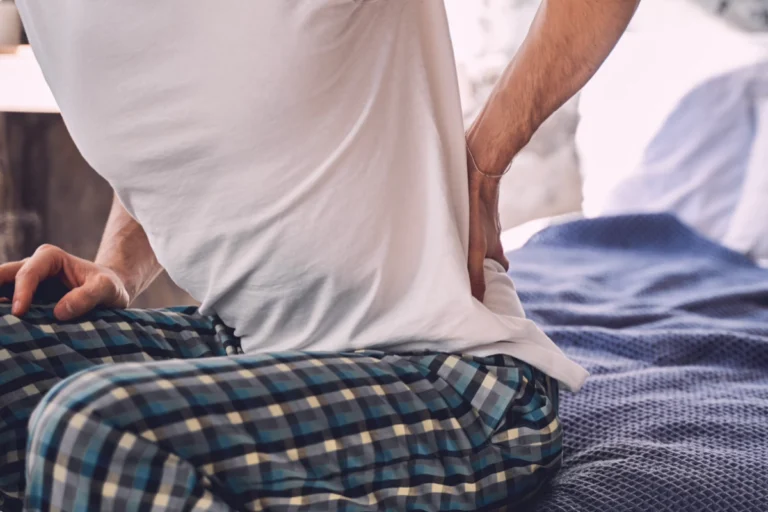 Persona tocando el cuello y el brazo con gesto de dolor causado por un nervio pinzado que provoca irradiación, hormigueo y debilidad.