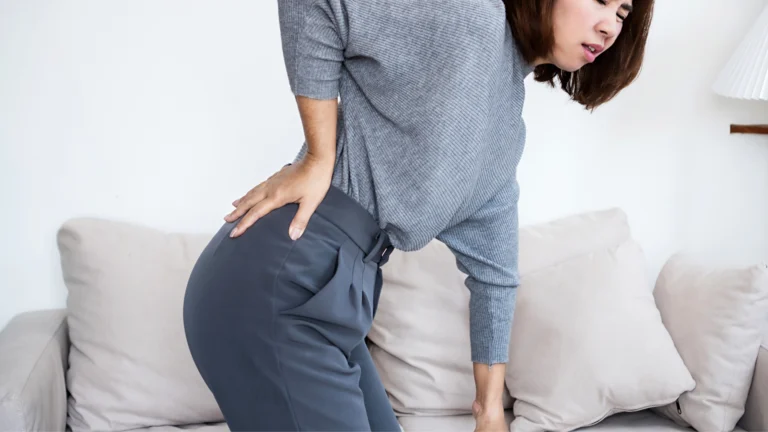 Person holding their lower back and leg due to pain from an inflamed sciatic nerve.