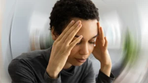 Person holding their neck while experiencing dizziness and loss of balance due to cervical vertigo.