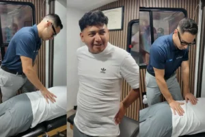 Trabajador latino con dolor de espalda baja por trabajo físico recibiendo atención quiropráctica