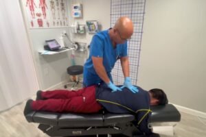 Doctor quiropráctico bilingüe atendiendo a paciente latino después de un accidente de auto en clínica ChiroDuo